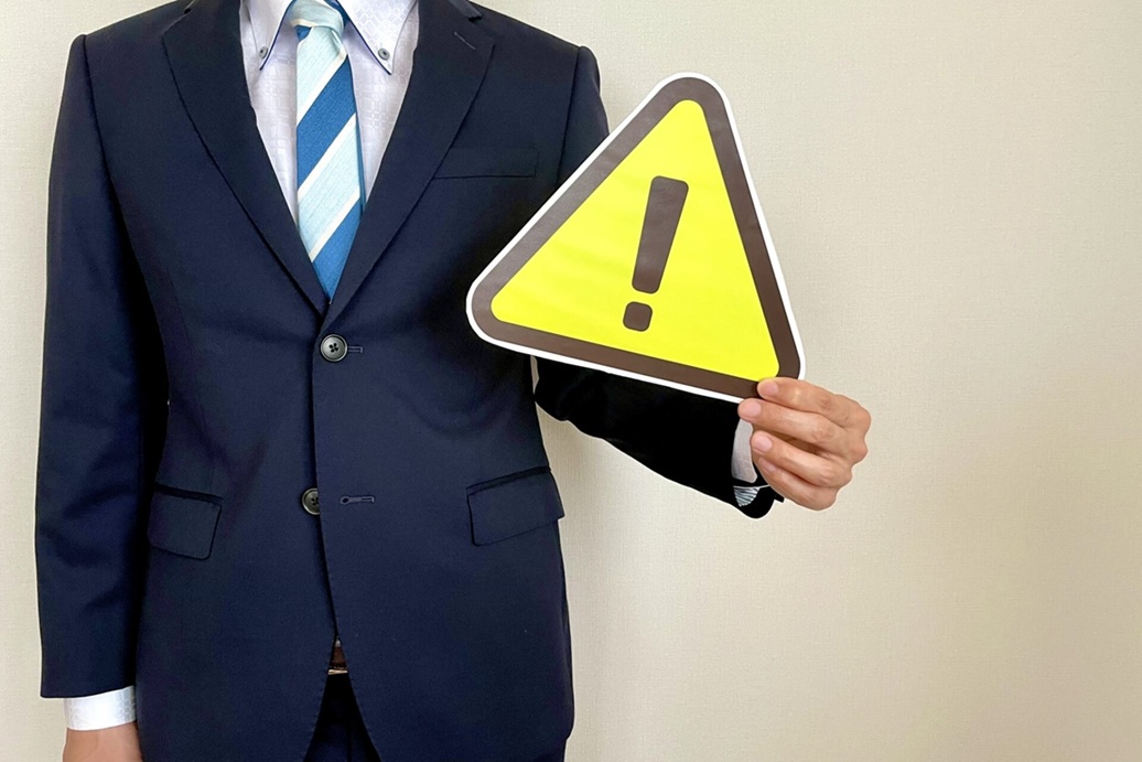 警告サインを持つスーツ姿の男性